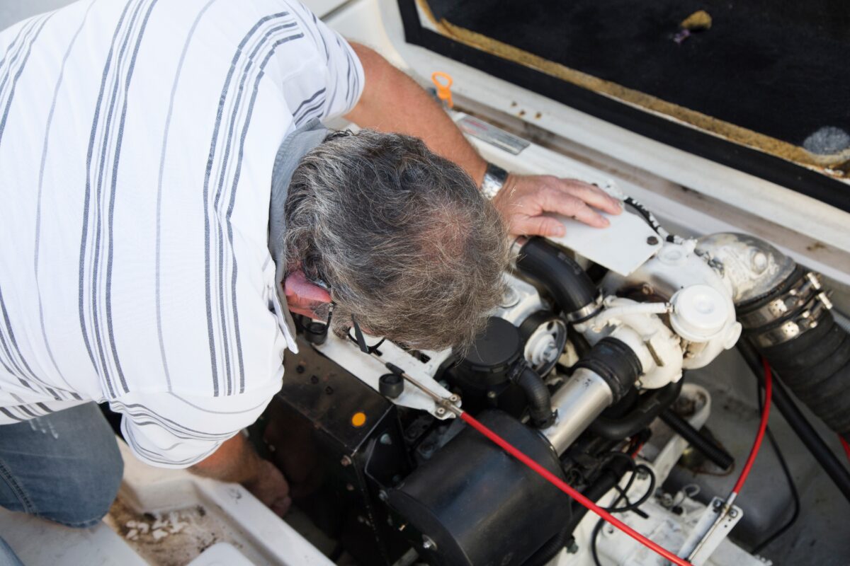 close-up of a man repairing a boat engine under sunny day